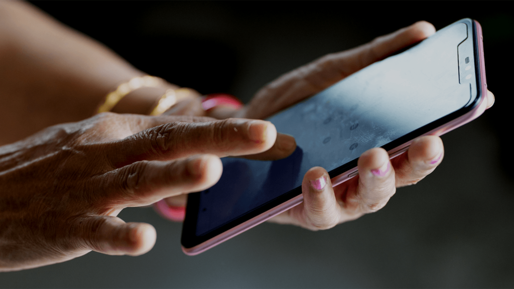 Hands of an older adult holding a smartphone.